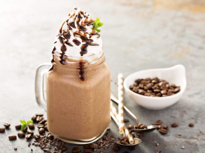 Chocolate frappe coffee with whipped cream and syrup on light background